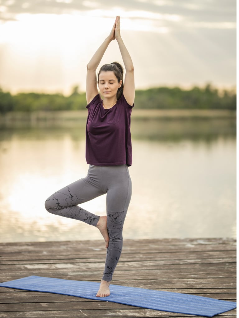 Junge Frau führt die Yoga-Übung Baumhaltung aus und demonstriert die richtige Ausführung.